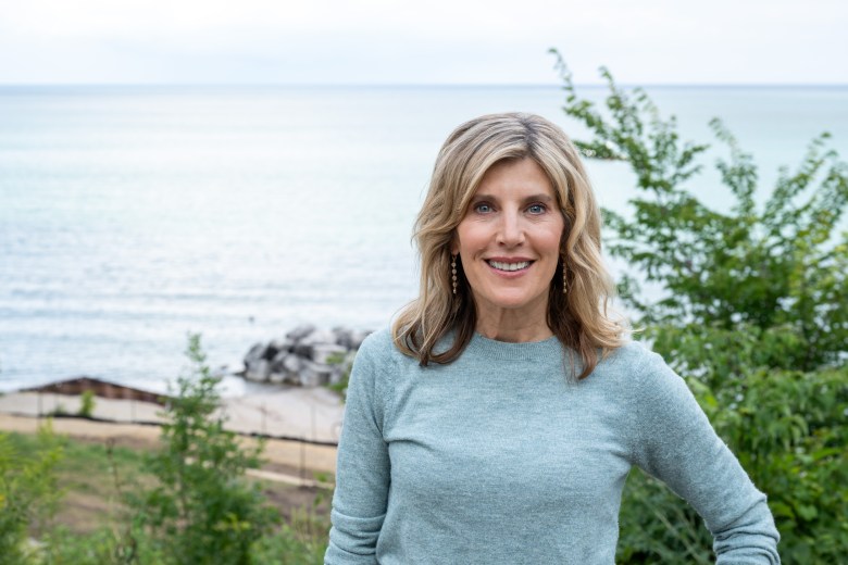 A blond woman in a light blue long-sleeved shirt next to water
