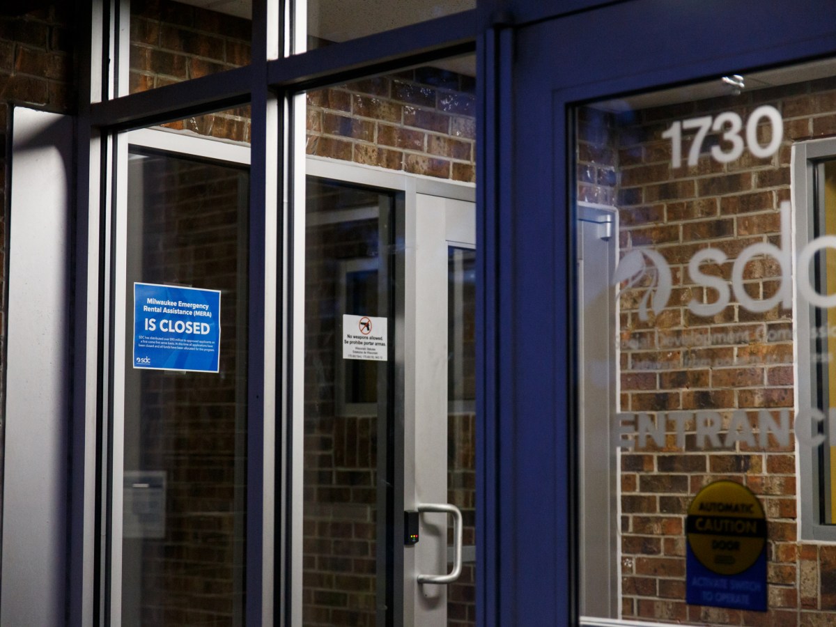 A blue "closed" sign is seen in glass entrance doors with the letters "SDC."