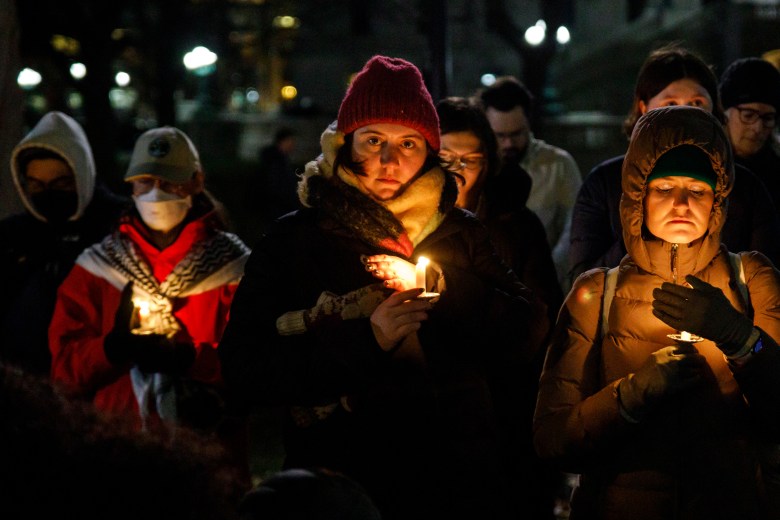 People hold lighted candles at night