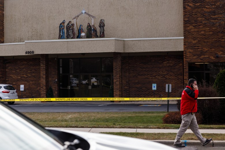 Person walks past yellow police tape in front of building with manger scene.