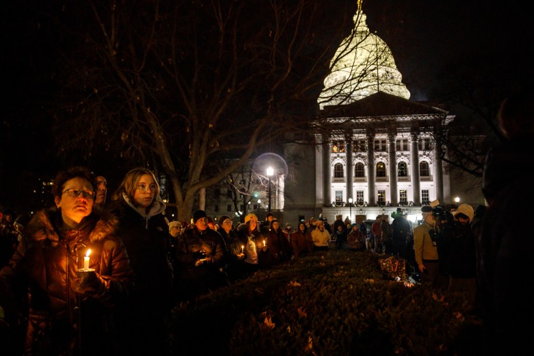 People hold candles outside of the Capitol